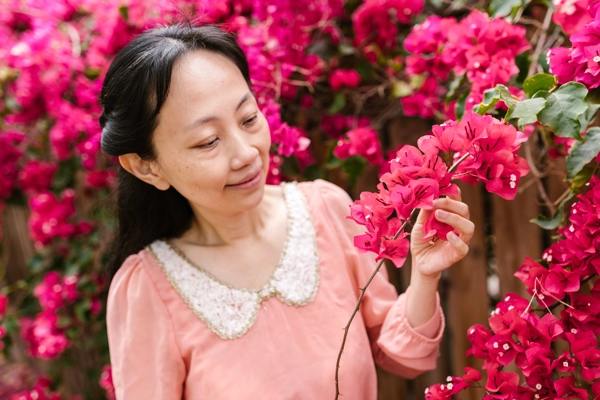 A woman standing in front of pink flowers